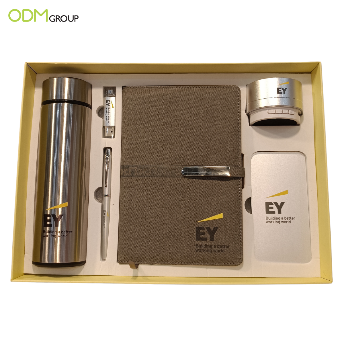 Corporate branded gift set including a thermos, notebook, pen, USB, and Bluetooth speaker.