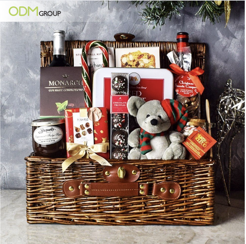 Luxurious Christmas-themed gourmet gift basket with festive treats and a teddy bear.