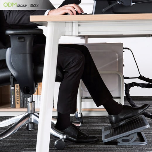 Man using an under-desk footrest while working at his desk.