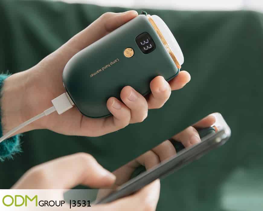 Hand holding a portable power bank while charging a phone.